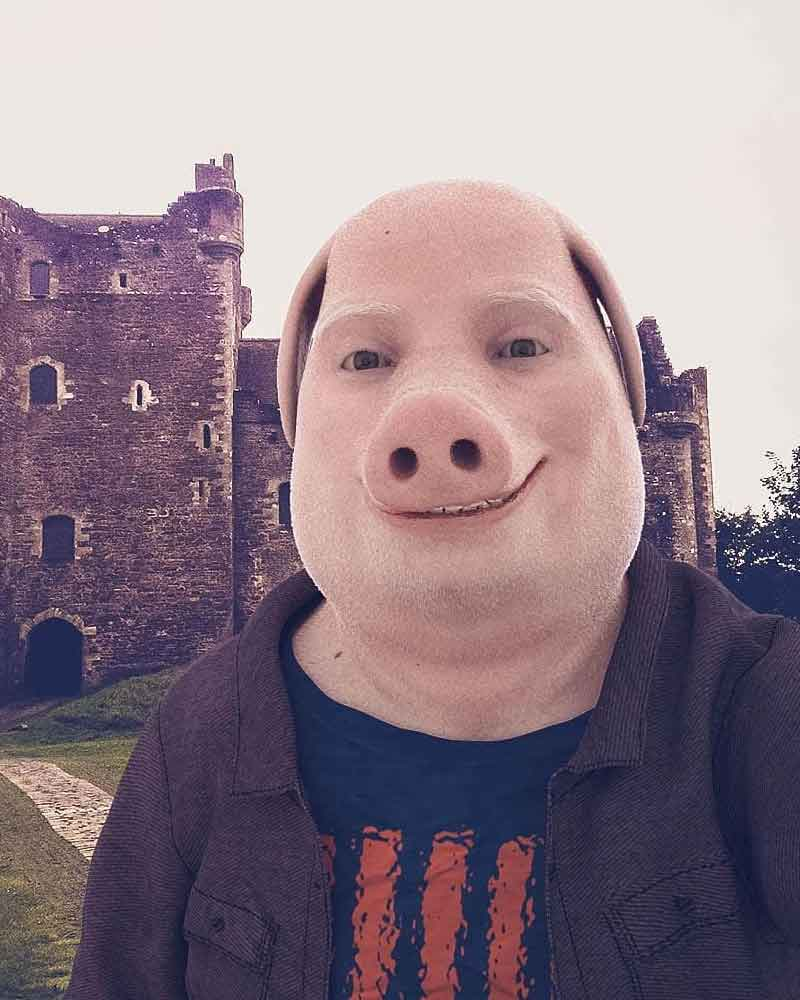 A smiling pig-masked figure standing before an ancient stone castle